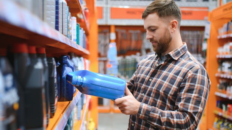 Man staring at a bottle of engine oil in a store