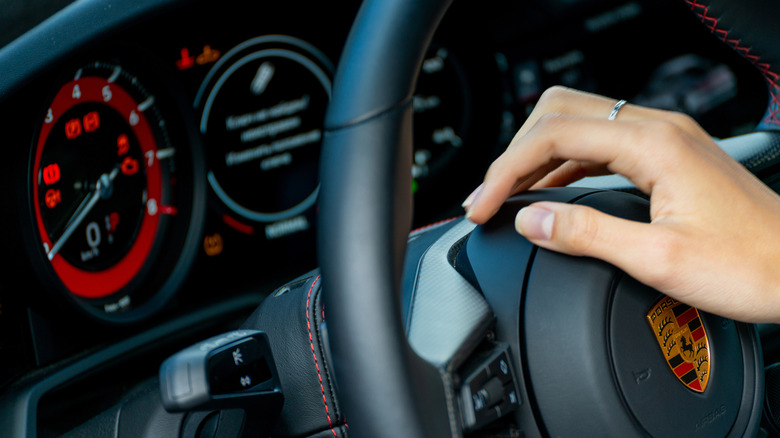 Hand on a Porsche steering wheel