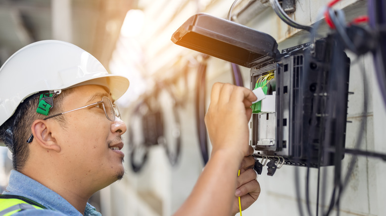 Technician checking fiber-optic box outside building
