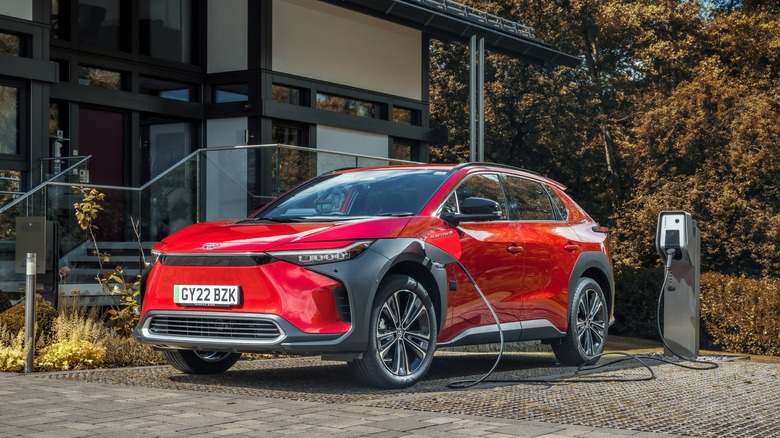 Front-quarter shot of a 2022 Toyota bZ4X plugged in outside a house