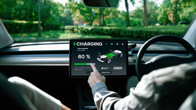 A person behind the wheel of a Tesla checking the charging state.