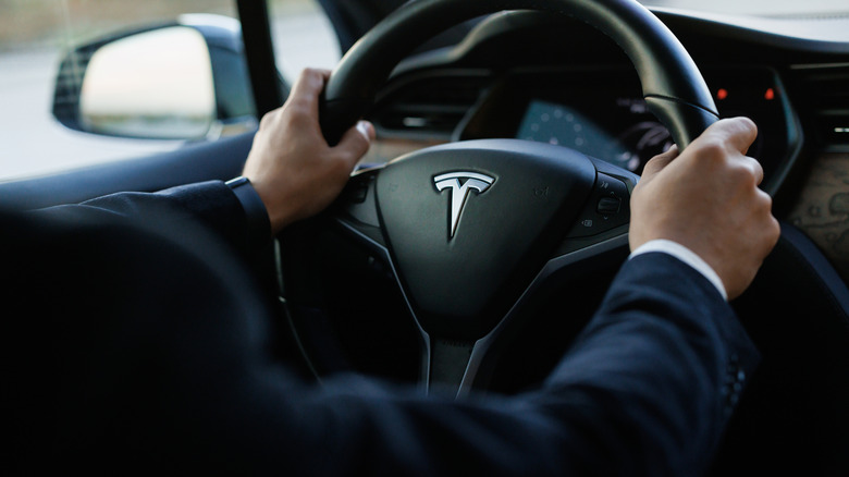 Closeup of a Tesla driver holding the steering wheel
