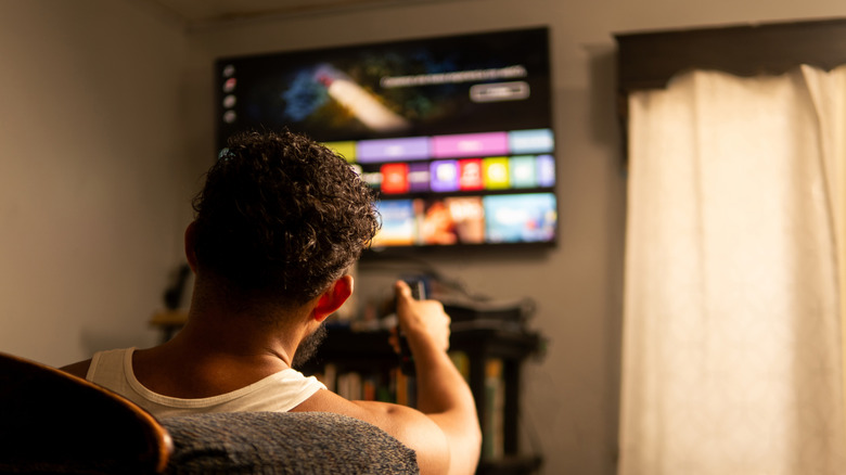 Man holding remote aimed at smart TV