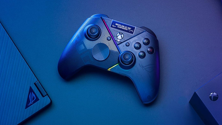 A blue Asus game controller kept in between a Windows laptop and an Xbox