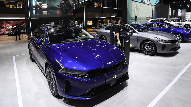 A lineup of Kia K5 models on a showroom floor