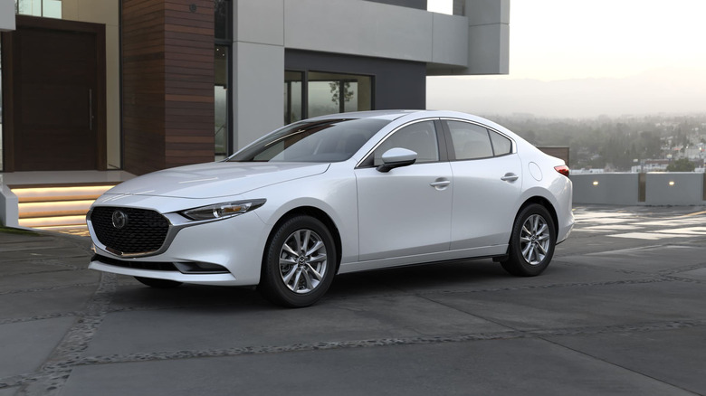 A white Mazda 3 parked in front of a house