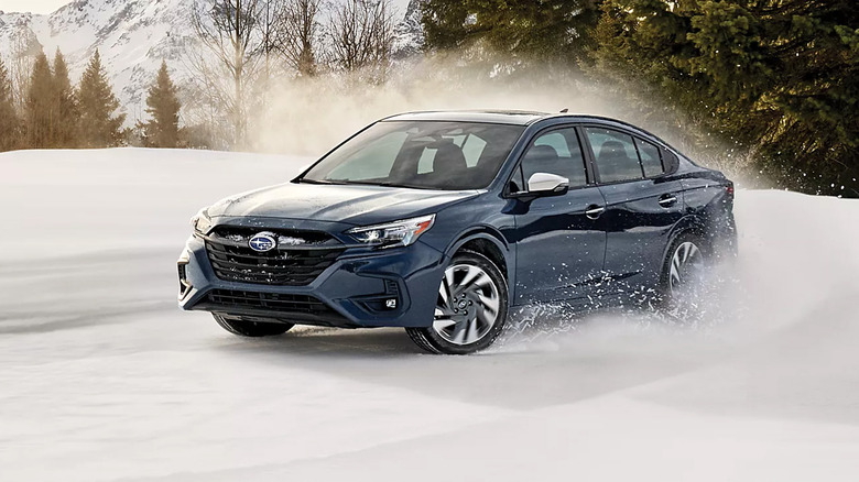 A blue Subaru Legacy driving in the snow