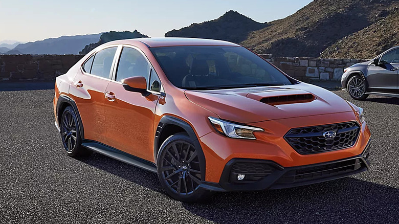 An orange Subaru WRX parked in the hills