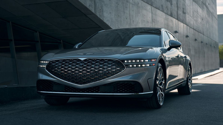 A gray Genesis G90 driving under an overpass