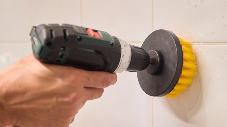A person using a drill with a brush attachment.