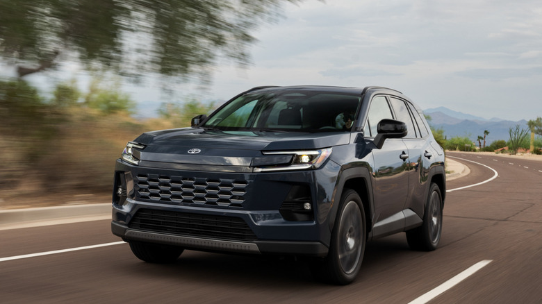 Black 2026 Toyota RAV4 driving on a rural road