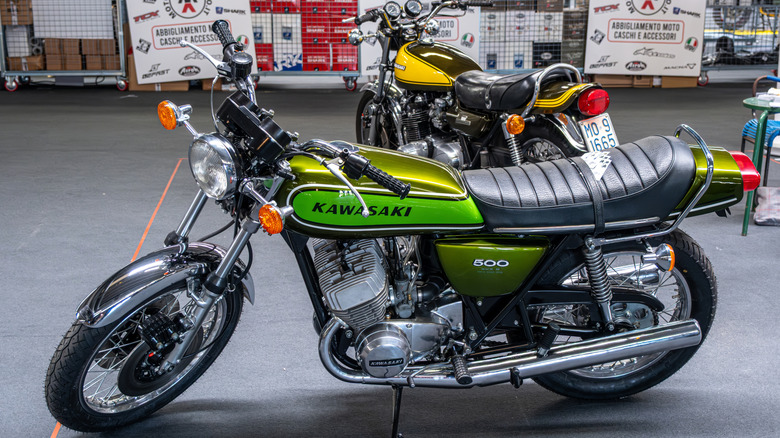 Two Kawasaki H1 Mach III motorbikes, one green in the foreground and one yellow in the background.