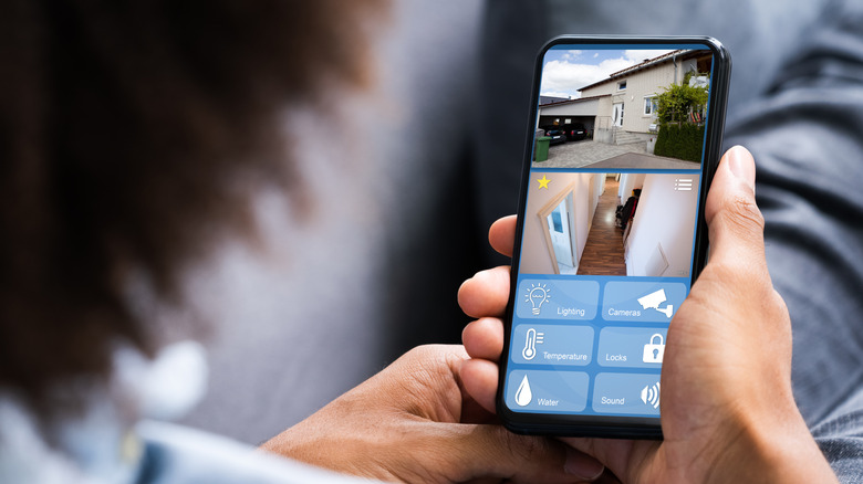 Person lounging on a couch while looking at their home security camera footage via smartphone