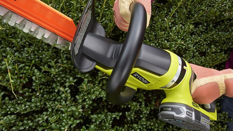 person using ryobi hedge trimmer