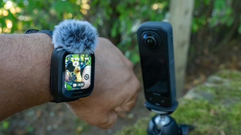 The GPS Preview Remote with Mic next to the Insta360 X5, worn on a wrist with a deadcat windmuff.