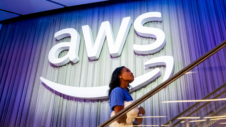 A person passing in front of an AWS logo