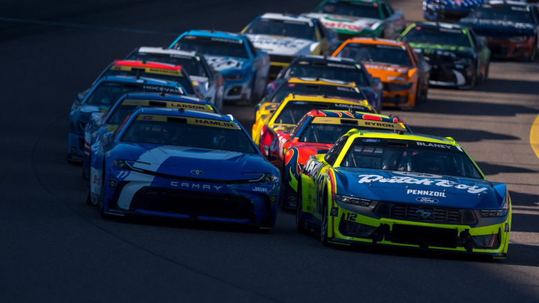 NASCAR race with cars bunched together on a turn