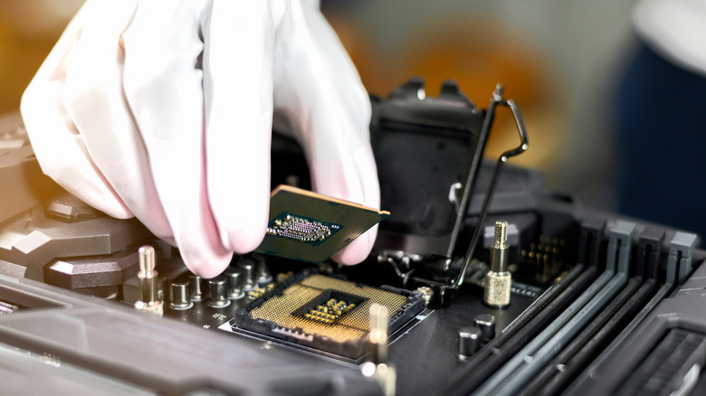 A technician's gloved hand placing a CPU into its motherboard slot