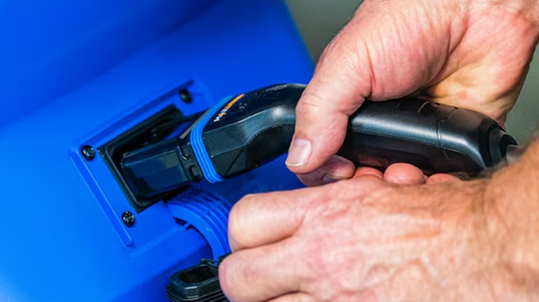 A person charging an electric Kobalt lawn mower