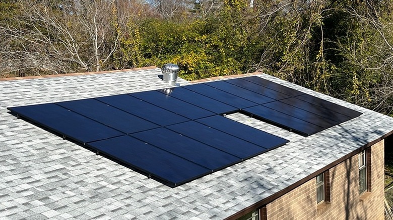 REC Solar panels installed on a house roof in the woods.