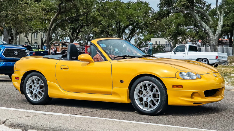 A yellow 2002 Mazda Miata arriving at a local car show