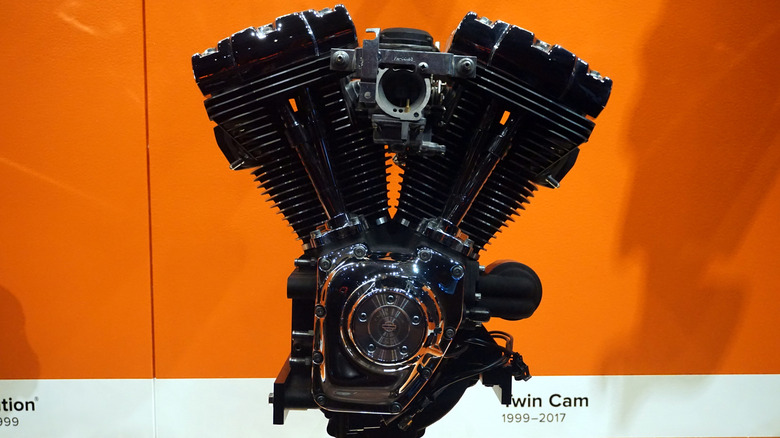 Harley-Davidson Twin Cam engine in museum display against orange background