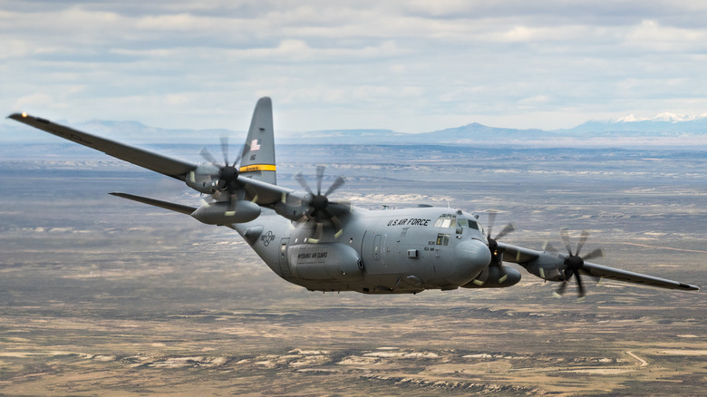 Hercules C-130J in flight over desert terrain