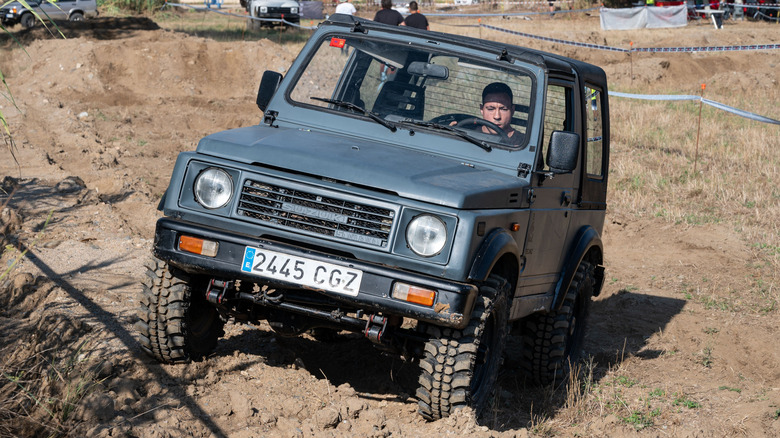 A Suzuki Samurai driving in a field.