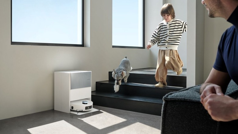 The Dreame Aqua10 Ultra Roller in its base station near a child and a dog.