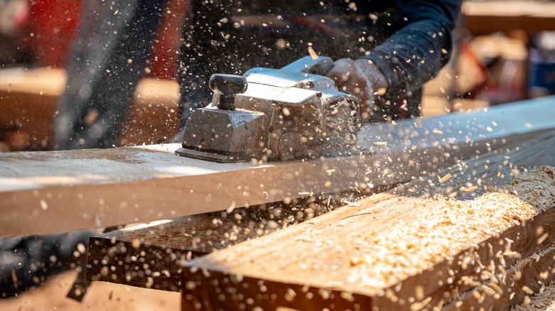 A person kicking up sawdust while woodworking
