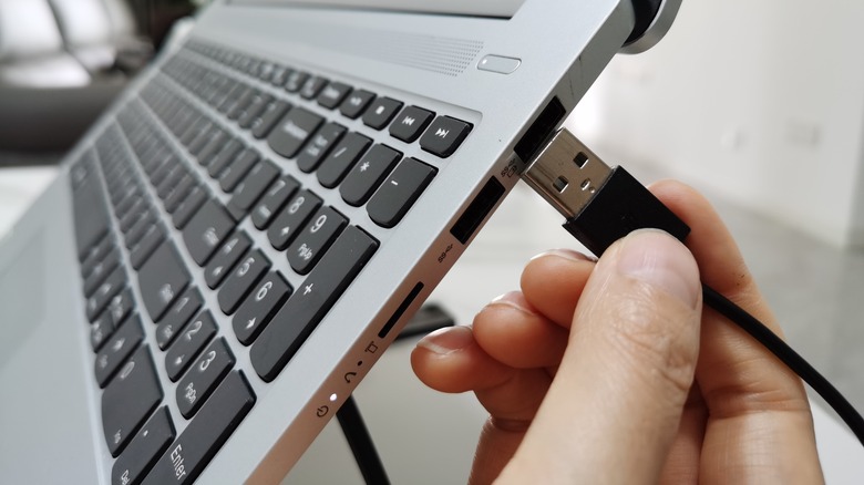 Person plugging USB cable into a laptop