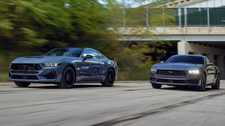 Ford Mustang EcoBoost and GT Fastback models driving on a road with a bridge in the background