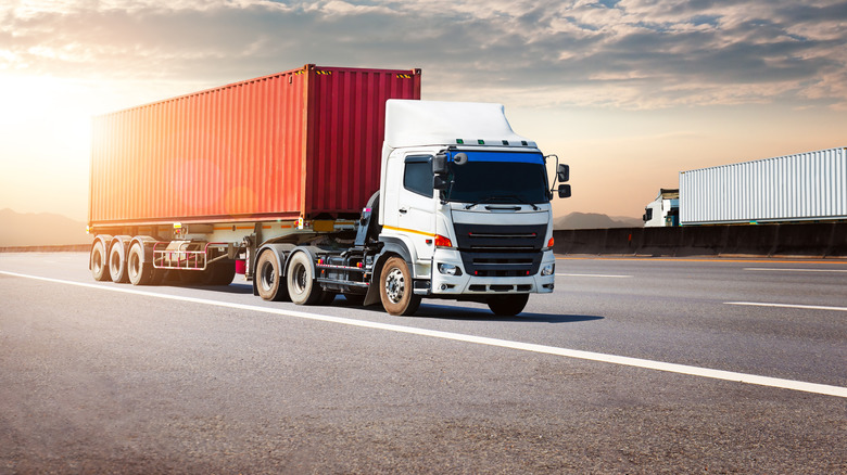 Semi Trailer Trucks Driving on High Way at The Sunset