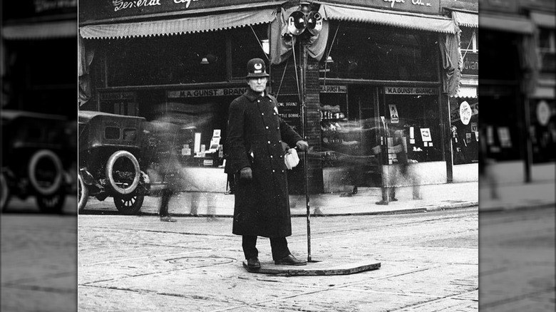 Policeman standing next to a "stop light" directing traffic in Seattle, Washington, circa 1922.