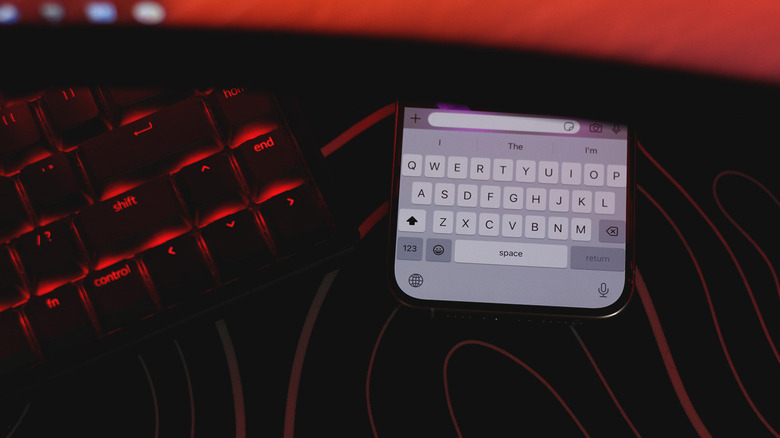 Physical keyboard next to an iOS keyboard, red ambient lighting