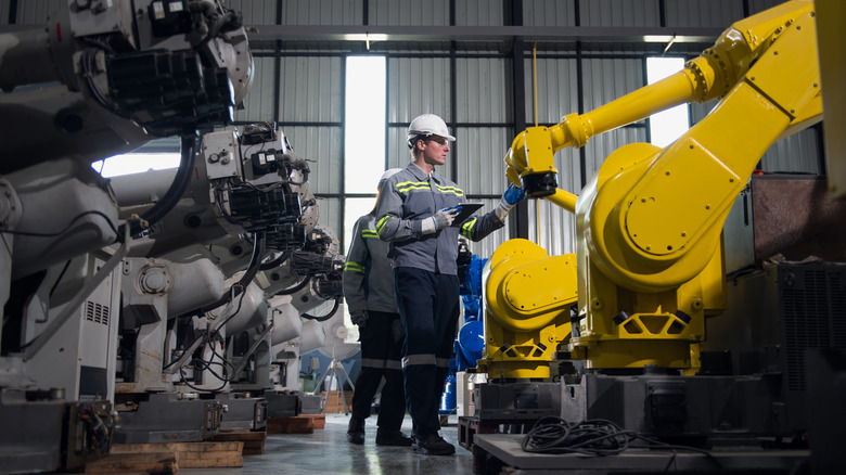 Workers inspect a robotic arm