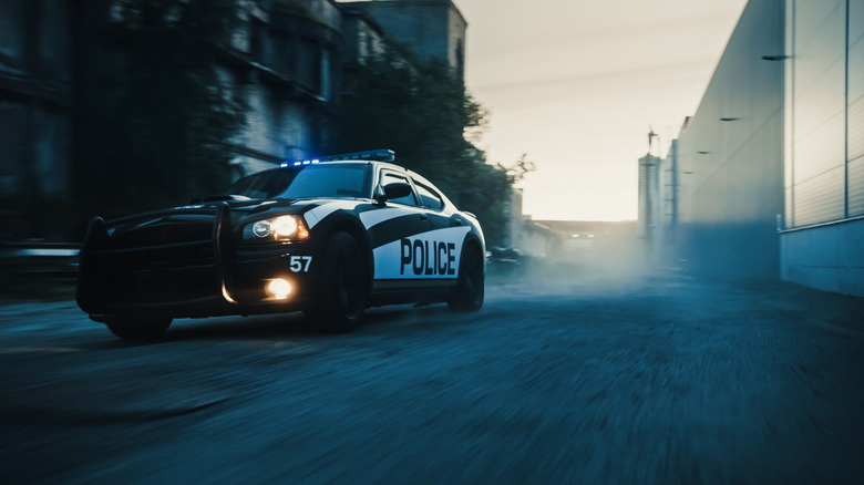 Police car in city alley with headlights on