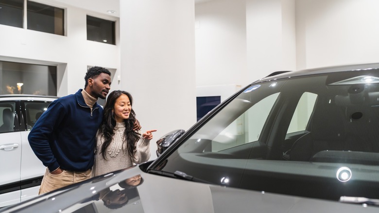 A couple choosing a car in dealership showroom