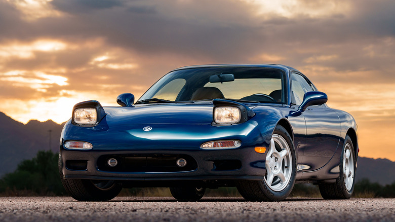 Blue 1994 Mazda RX7 with headlights open and on