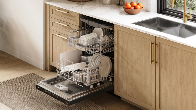 A modern kitchen featuring an open Bosch dishwasher filled with dishes.