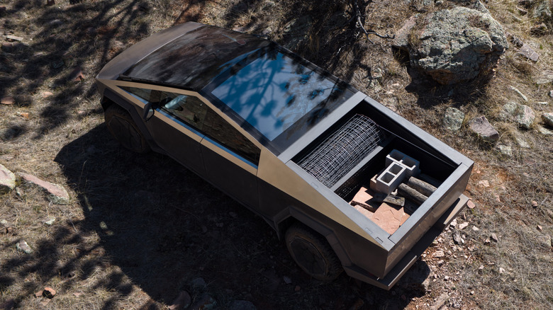Overhead rear view of Tesla Cybertruck in rocky forested setting