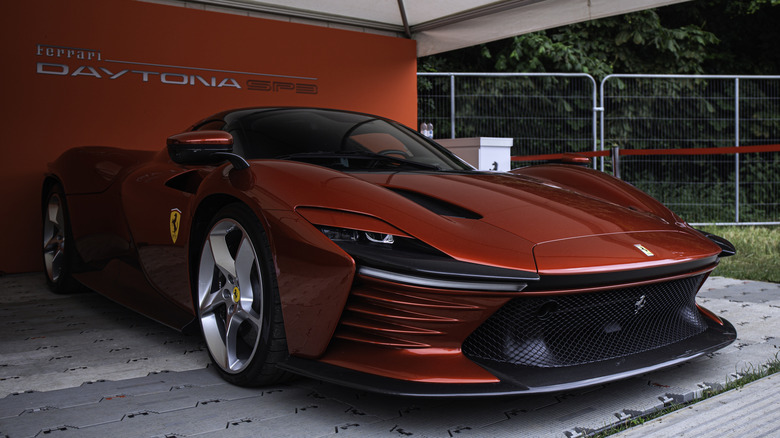 A bright red Ferrari Daytona SP3 showcased in a Ferrari booth.