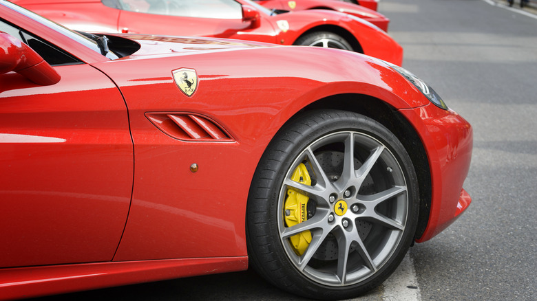 A row of bright red Ferraris parked side by side on a city street.