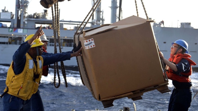 U.S. Navy crews handling cargo from a Military Sealift Command ship.