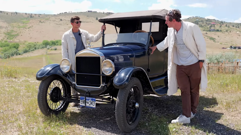 Two men standing next to a blue Fort Model T truck