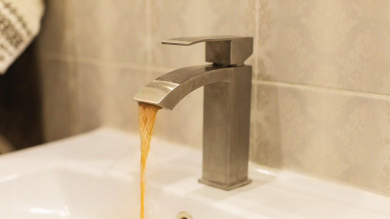 a faucet running producing brown water