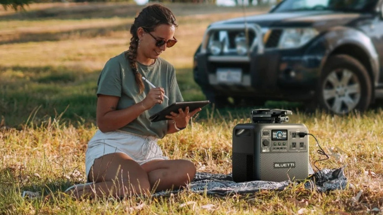 Woman using Bluetti portable power station outdoors