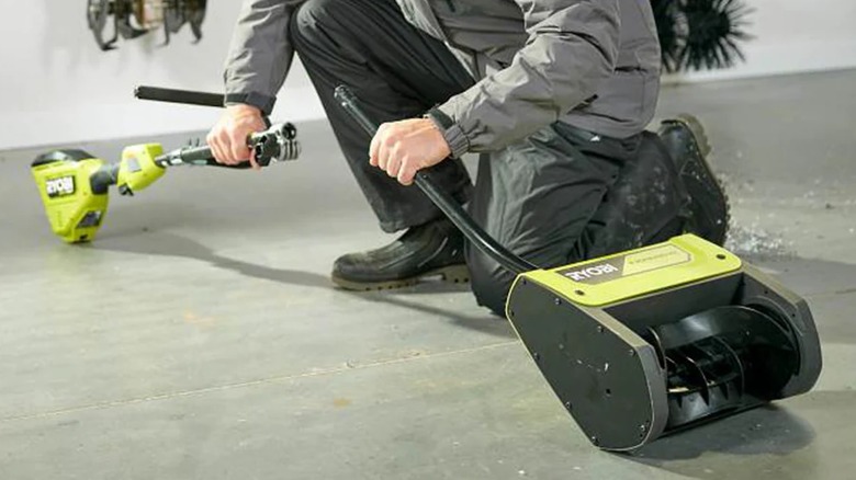 A person connecting a Ryobi string trimmer to a snow blower attachment.