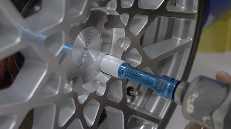 A close-up of a person handling an impact wrench with a non-marring socket to tighten lug nuts.