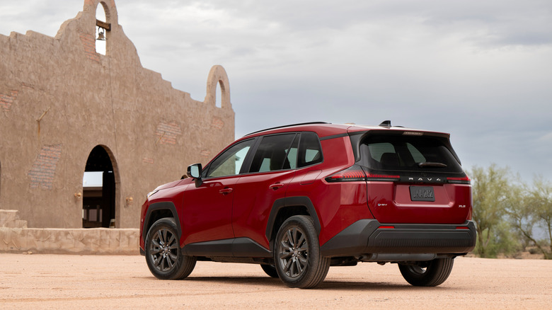 Rear-quarter shot of a 2026 Toyota RAV4 in red with gray wheels